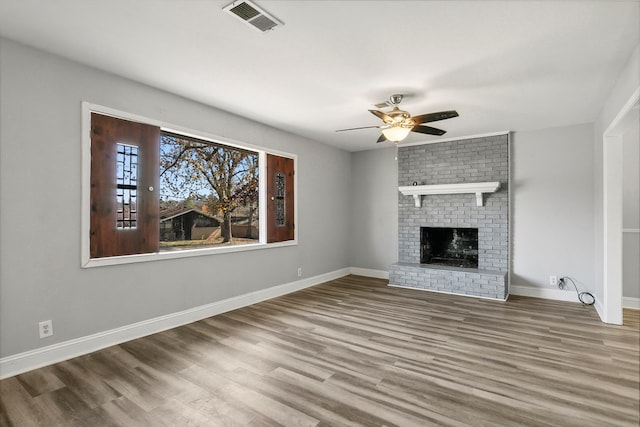 unfurnished living room with visible vents, a fireplace, baseboards, and wood finished floors