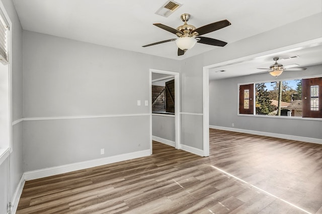 spare room with wood finished floors, visible vents, and baseboards