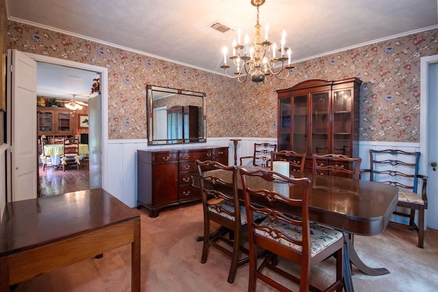 carpeted dining area with ceiling fan with notable chandelier and ornamental molding