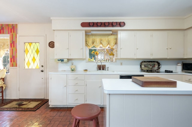 kitchen featuring a breakfast bar, white cabinetry, dishwashing machine, and sink