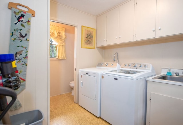 clothes washing area with washer and dryer, cabinets, and sink