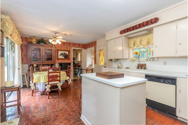 kitchen with white dishwasher, white cabinetry, a kitchen island, and sink