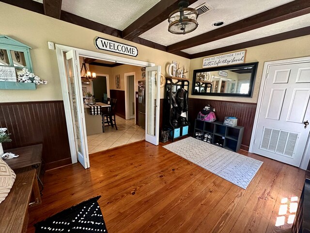 interior space featuring beam ceiling, a textured ceiling, hardwood / wood-style flooring, and an inviting chandelier