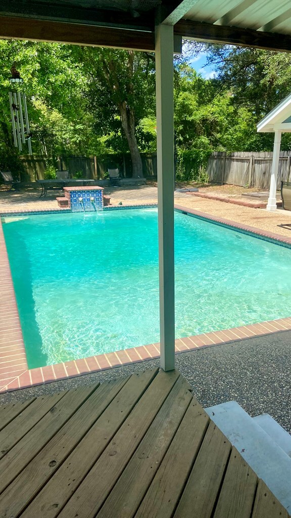 view of pool with a wooden deck, pool water feature, and a hot tub