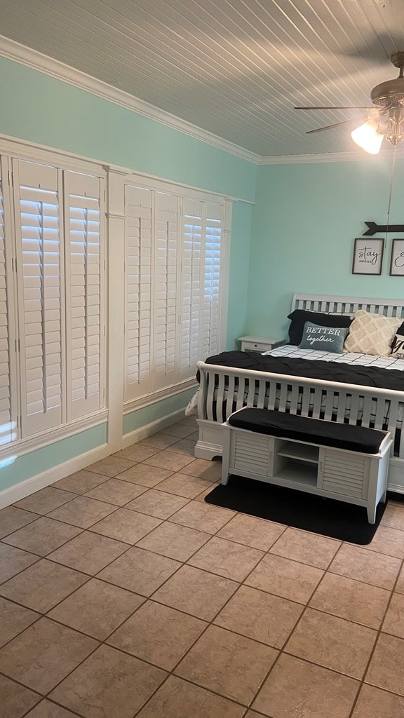 bedroom with ceiling fan, light tile patterned floors, crown molding, and wood ceiling