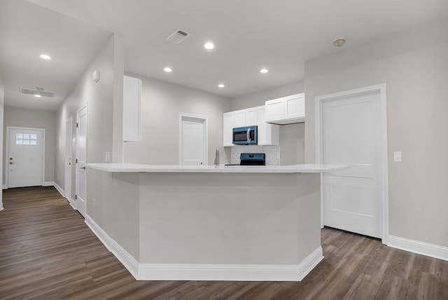 kitchen featuring kitchen peninsula, black stove, backsplash, dark wood-type flooring, and white cabinets