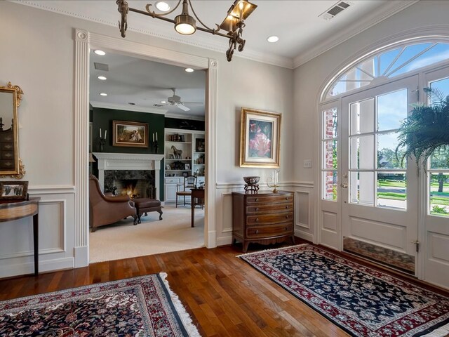 entryway featuring wood-type flooring, ceiling fan, ornamental molding, and a premium fireplace