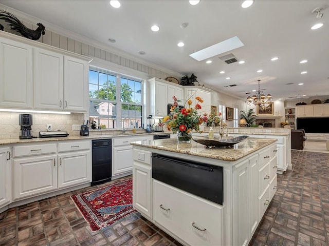 kitchen featuring a skylight, a kitchen island, white cabinets, and ornamental molding