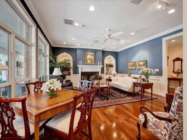 dining space featuring wood-type flooring, ceiling fan, and crown molding