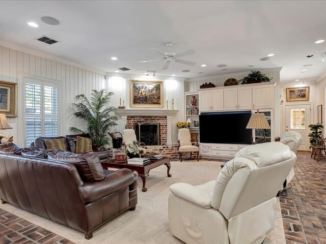 living room featuring crown molding, ceiling fan, and a brick fireplace