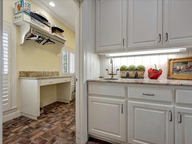 kitchen with white cabinets, backsplash, light stone counters, and sink