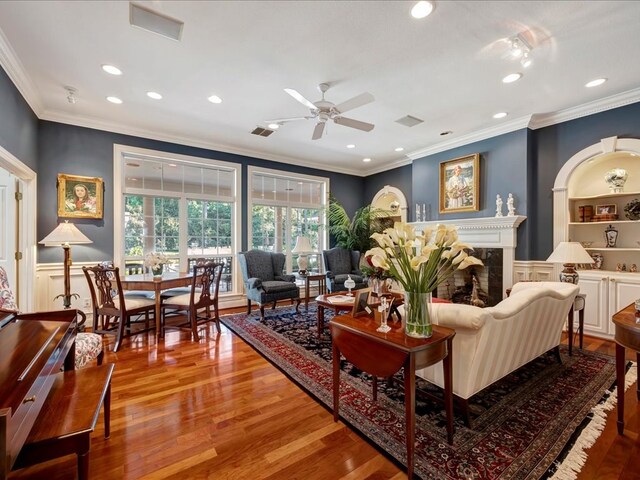 living room with hardwood / wood-style flooring, ceiling fan, and ornamental molding