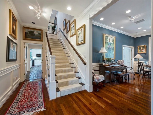 staircase featuring wood-type flooring and ornamental molding