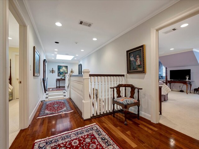 corridor with dark hardwood / wood-style flooring, ornamental molding, and a skylight