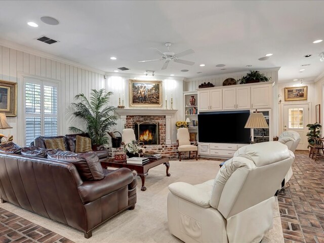 living room featuring ceiling fan, a fireplace, and ornamental molding