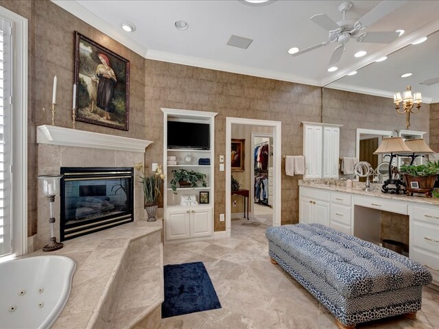 bathroom with a tub to relax in, vanity, ceiling fan, crown molding, and a fireplace