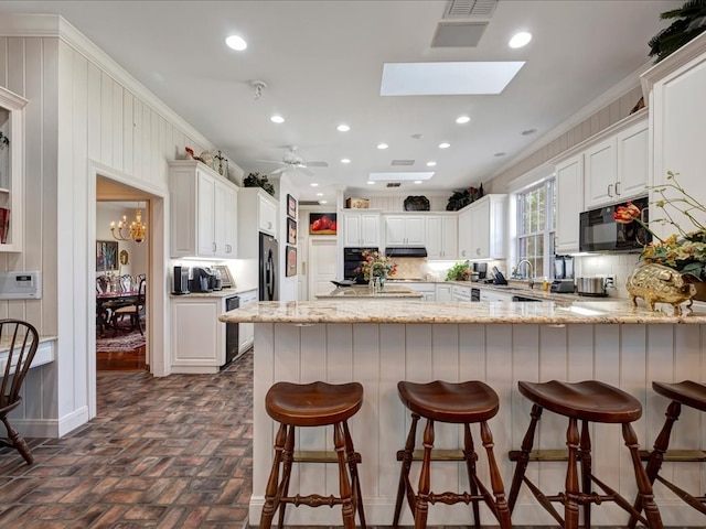 kitchen featuring kitchen peninsula, backsplash, white cabinets, and crown molding