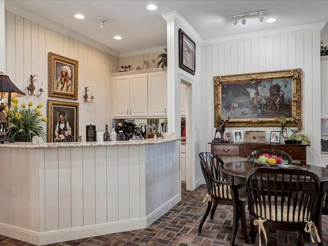 kitchen with white cabinets, light stone counters, crown molding, and wood walls