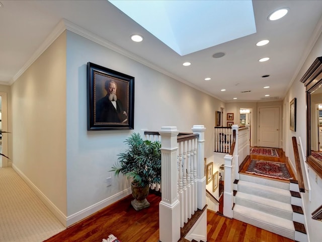 corridor featuring hardwood / wood-style flooring, ornamental molding, and a skylight