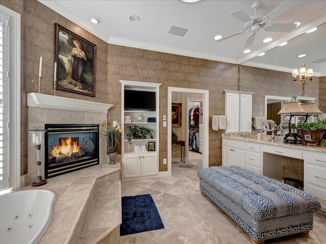 bathroom featuring ceiling fan, a washtub, crown molding, a tiled fireplace, and vanity