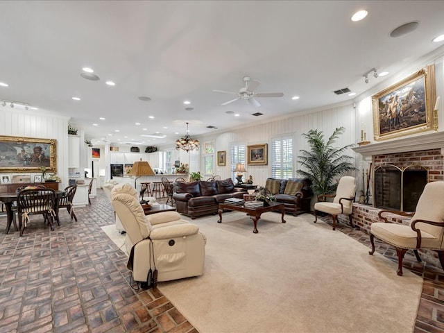 living room featuring a fireplace, ceiling fan with notable chandelier, and crown molding