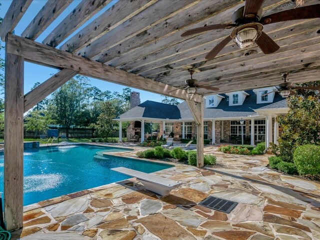 view of swimming pool with a patio area, ceiling fan, and a diving board