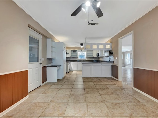 kitchen featuring white cabinetry, ornamental molding, light tile patterned flooring, and ceiling fan