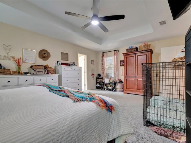 bedroom with carpet floors, a tray ceiling, and ceiling fan