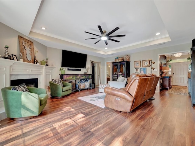 living room featuring a tray ceiling, ceiling fan, hardwood / wood-style floors, and crown molding