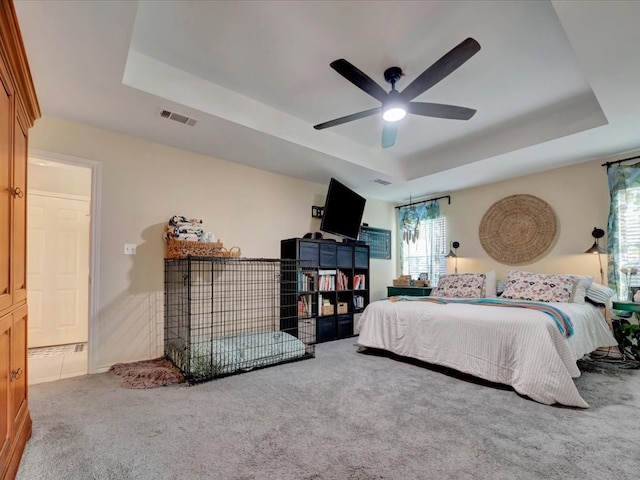 carpeted bedroom featuring a tray ceiling and ceiling fan