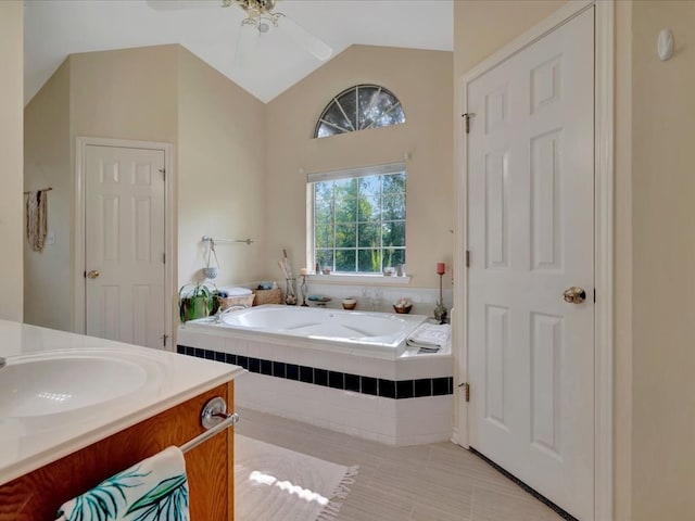 bathroom featuring vanity, ceiling fan, lofted ceiling, and tiled bath