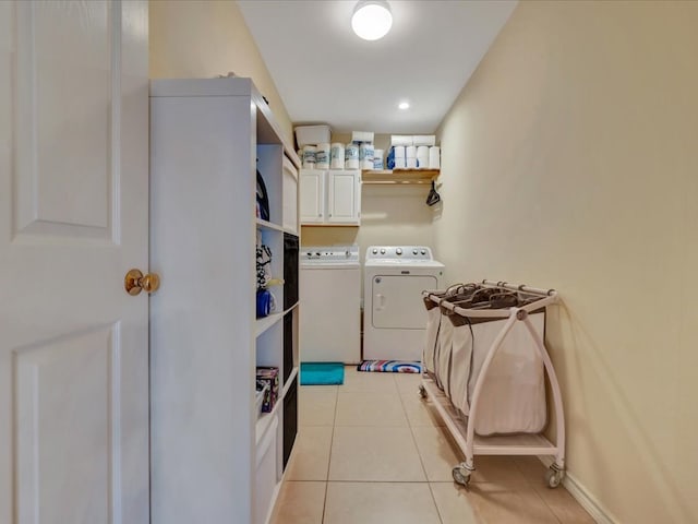 clothes washing area with washer and clothes dryer, light tile patterned flooring, and cabinets