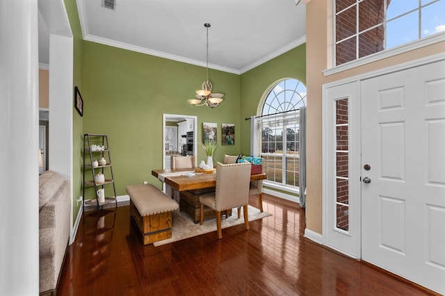 dining space with a towering ceiling, dark wood-type flooring, ornamental molding, and a chandelier