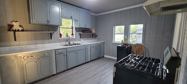 110 Hines St, Diboll, TX 75941 - kitchen featuring black gas stove, exhaust hood, plenty of natural light, light wood-style floors, and wooden walls