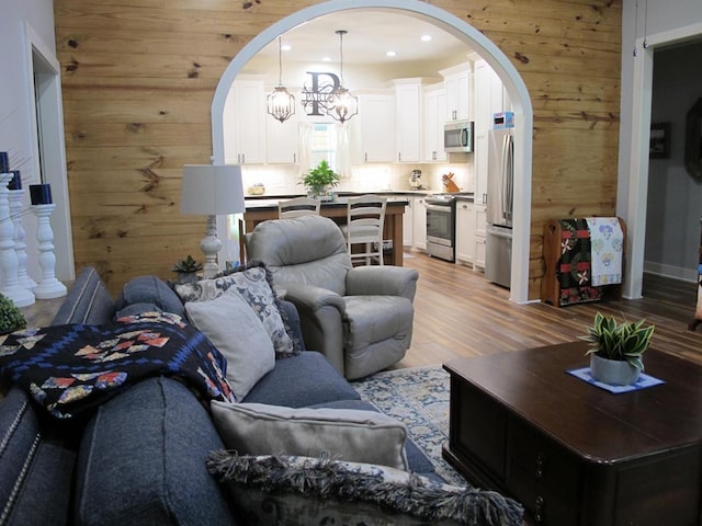 1208 Leslie Ln, Lufkin, TX 75901 - living area featuring arched walkways, wood walls, light wood-style floors, a chandelier, and recessed lighting