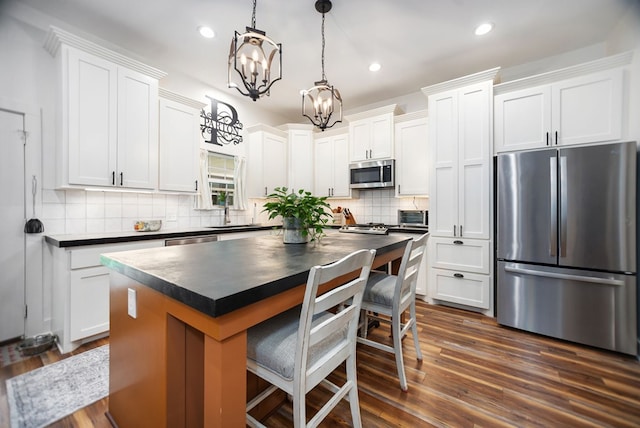1208 Leslie Ln, Lufkin, TX 75901 - kitchen with appliances with stainless steel finishes, dark countertops, a chandelier, tasteful backsplash, and recessed lighting