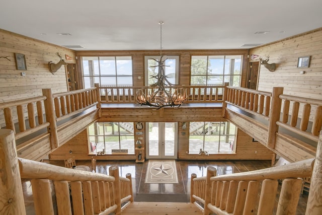 living room featuring plenty of natural light, wooden walls, and a chandelier