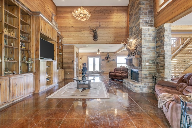 unfurnished living room featuring a stone fireplace, wooden walls, a towering ceiling, and ceiling fan