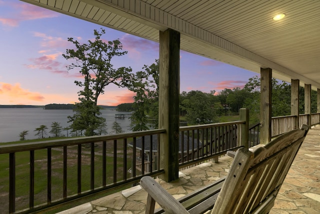 patio terrace at dusk featuring a water view