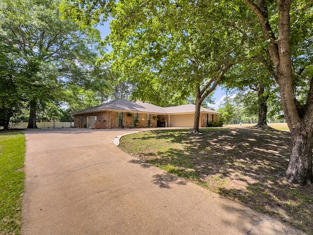single story home with an attached garage, fence, brick siding, and concrete driveway