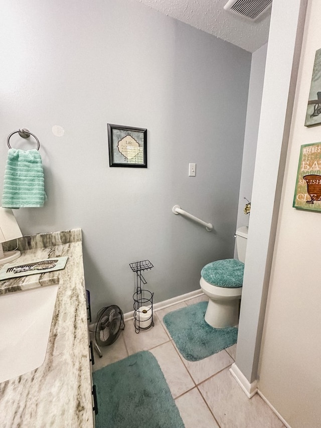 bathroom featuring tile patterned floors, visible vents, toilet, a sink, and baseboards
