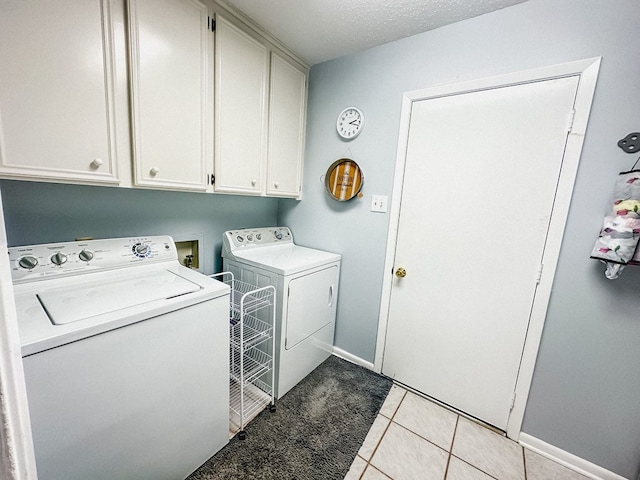 washroom featuring light tile patterned flooring, baseboards, washer and clothes dryer, and cabinet space