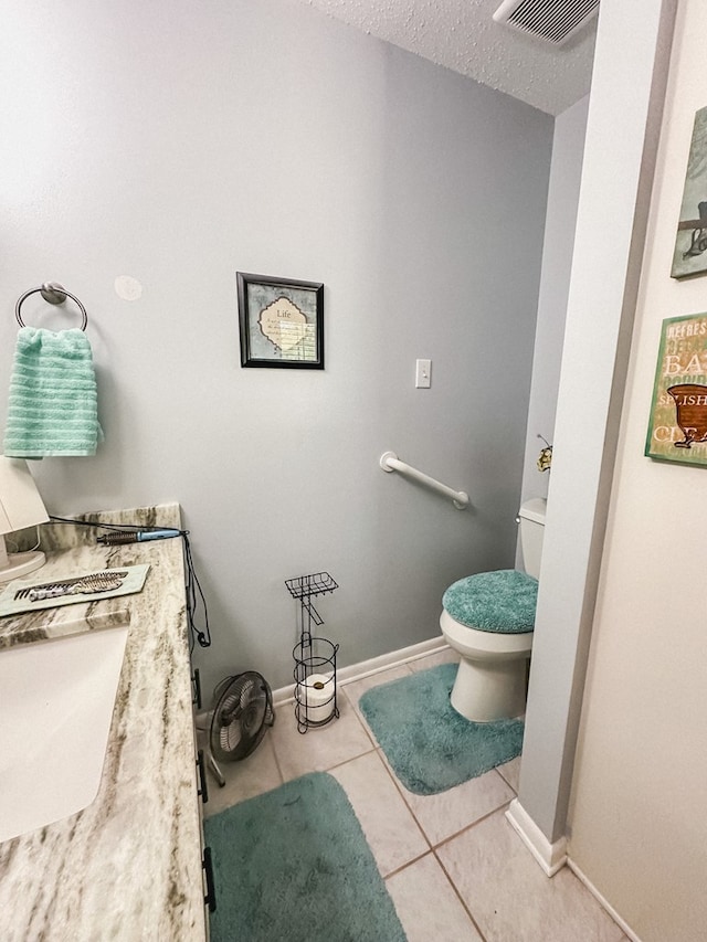 bathroom with a textured ceiling, toilet, baseboards, visible vents, and tile patterned flooring