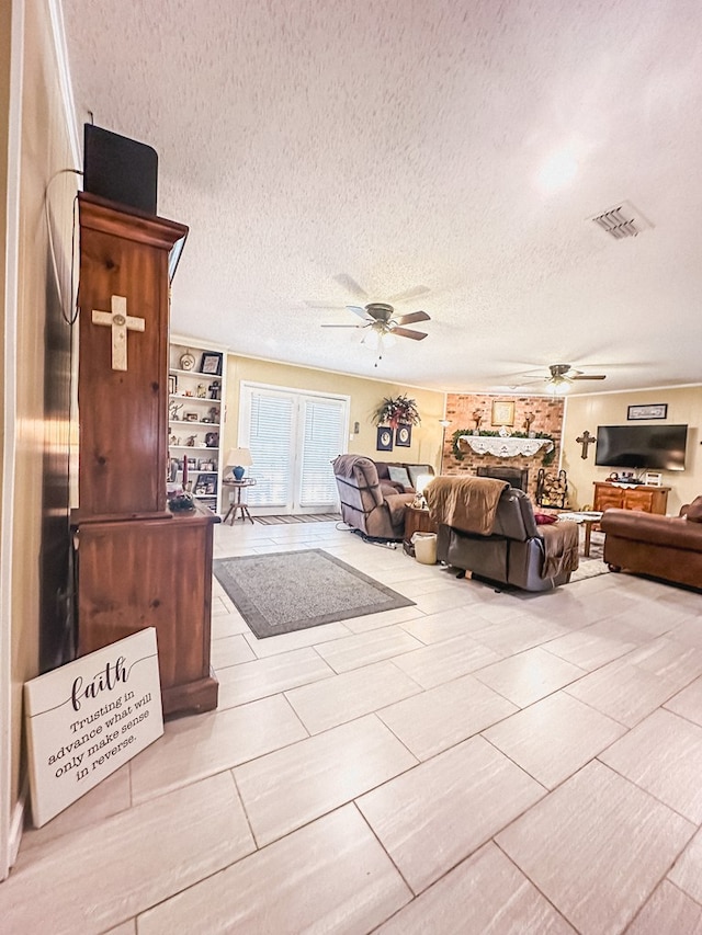 living room featuring a ceiling fan, visible vents, and a textured ceiling