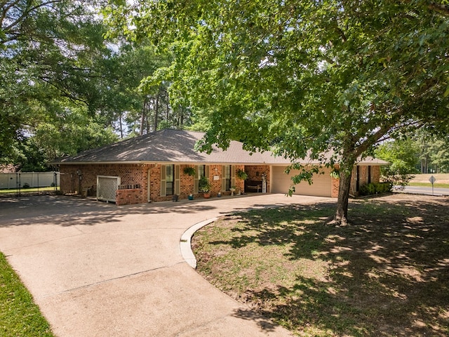 ranch-style house with brick siding, an attached garage, concrete driveway, and fence