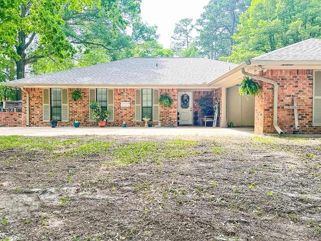 ranch-style house with brick siding, roof with shingles, and covered porch