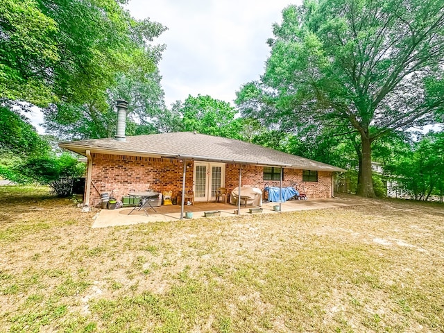 back of house featuring brick siding, french doors, a yard, and a patio