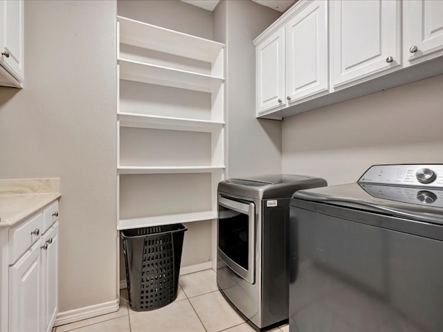 washroom featuring cabinets, light tile patterned floors, and washing machine and clothes dryer