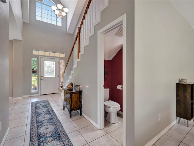 tiled entrance foyer featuring high vaulted ceiling and a chandelier