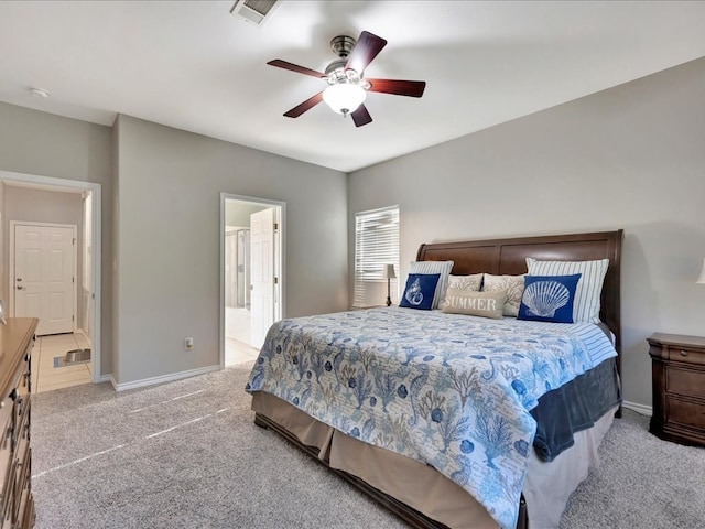 bedroom with light carpet, ensuite bathroom, and ceiling fan